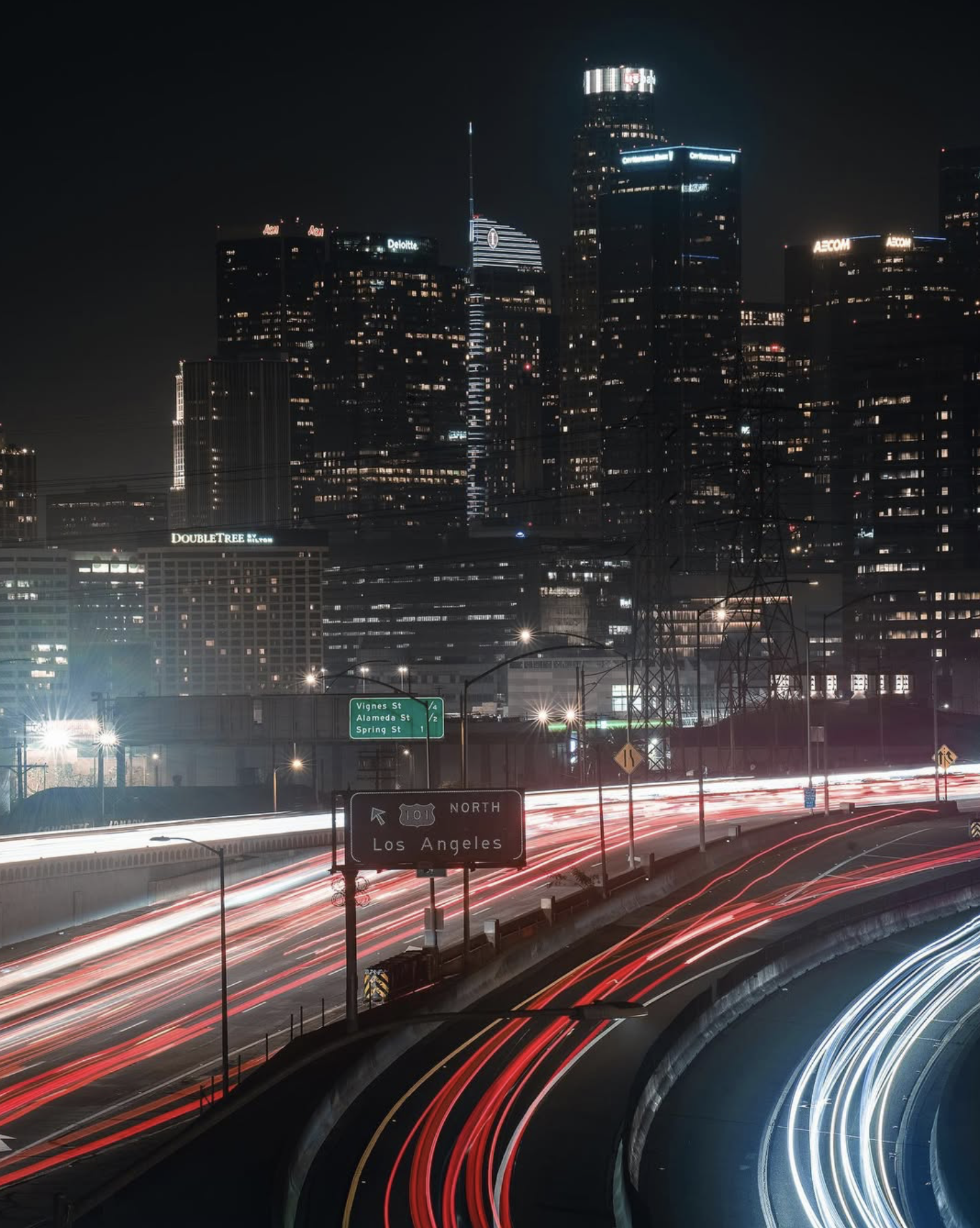 Long-exposure light trails on the 101 freeway with the downtown Los Angeles skyline at night