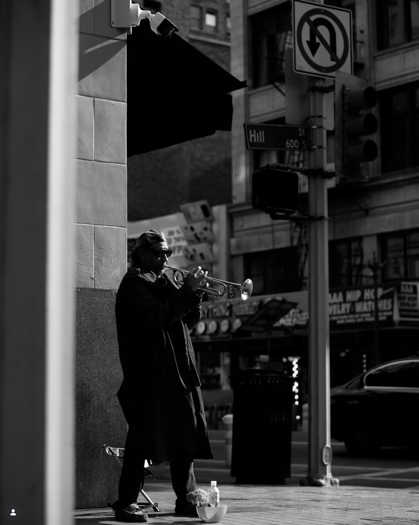 A street musician plays trumpet in a doorway on Hill Street, downtown Los Angeles